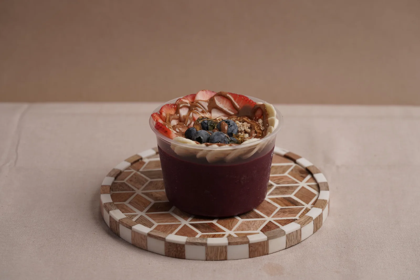 Açaí bowl topped with berries on a checkered coaster